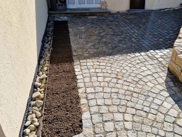 Granitpflaster mit Kiesstreifen an der Hauswand